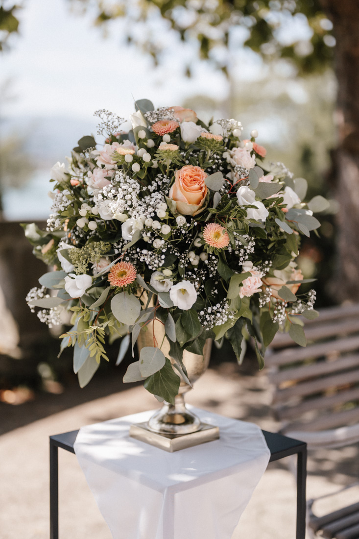 Blumenarrangement mit Rosen und Schleierkraut in goldener Vase auf Tisch