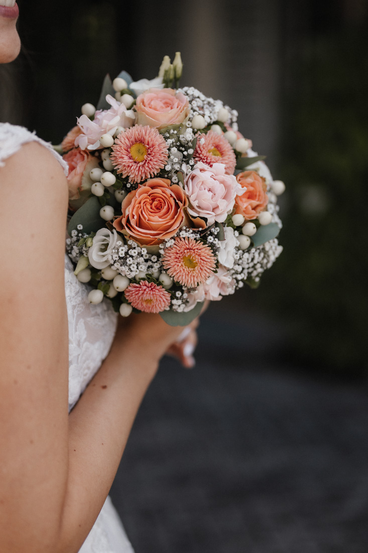 Frau hält Blumenstrauss mit Rosen und kleinen weissen Beeren in den Händen
