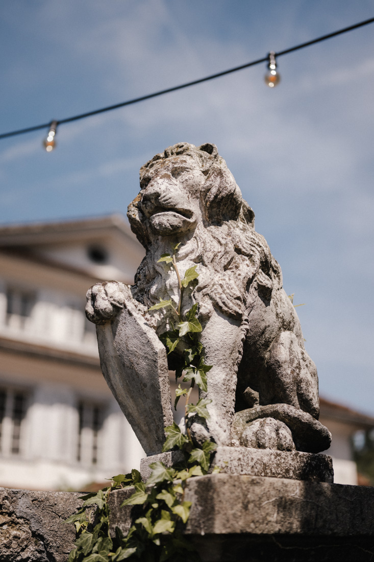 Steinstatue eines Löwen mit Schild und Efeu vor Hotel Seeburg