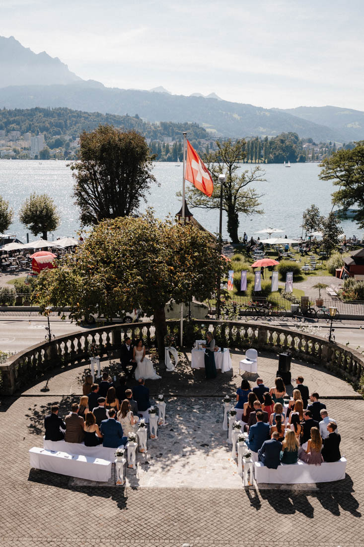 Menschen sitzen bei Zeremonie mit Schweizer Flagge und See
