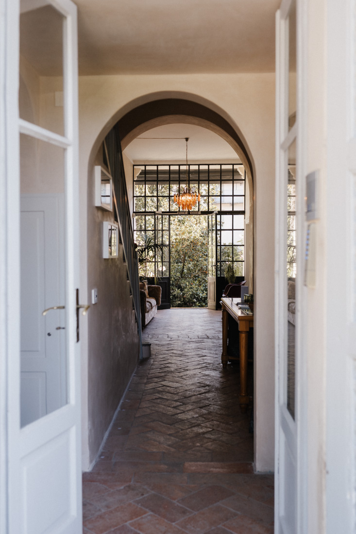 Offene weisse Türen mit Blick auf Flur mit Ziegelboden und Treppe