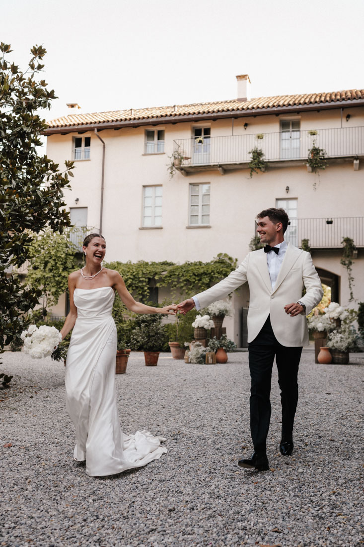 Frau mit Blumenstrauss und Mann mit Fliege halten Hände