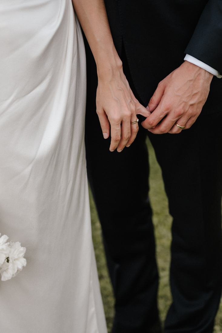 Händchenhalten mit Ringen und schwarzem Anzug und weissem Kleid