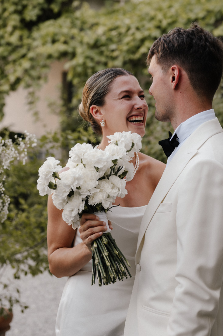 Lachende Frau mit weissen Blumen und Mann mit Fliege im Garten