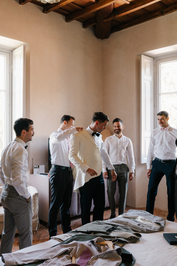 Gruppe Männer in Hemden und Anzughosen in einem Zimmer mit Fenstern