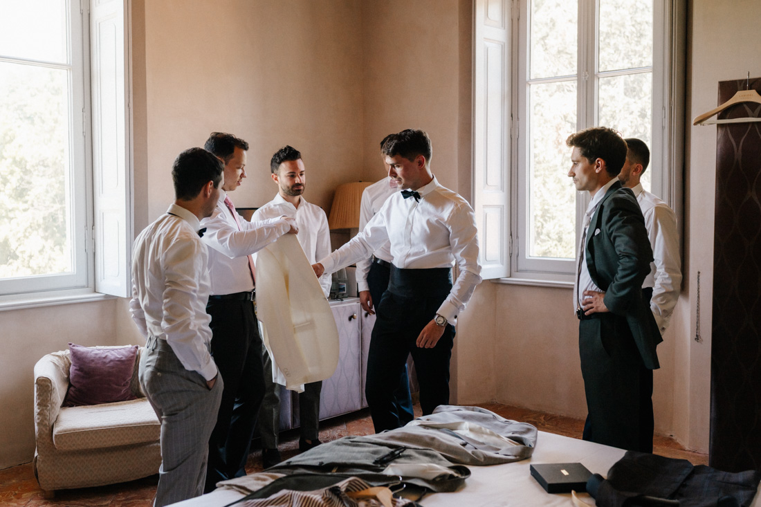Gruppe Männer mit Hemden und Anzügen in einem Zimmer mit Fenster