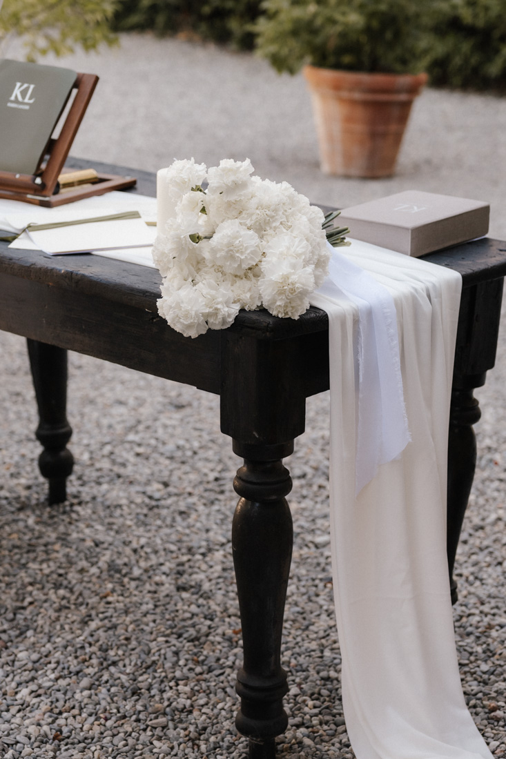 Tisch mit weissem Blumenstrauss Stoff und Buch mit Initialen