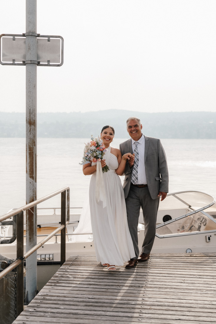 Frau im weissen Kleid mit Blumenstrauss und Mann im grauen Anzug auf Steg