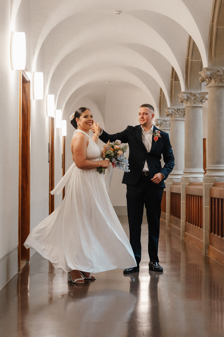 Brautpaar im Gang mit Blumenstrauss und weissem Kleid