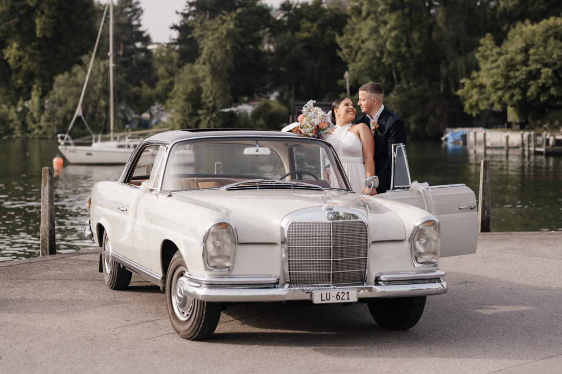 Brautpaar am See mit Oldtimer Mercedes und offenem Autotür