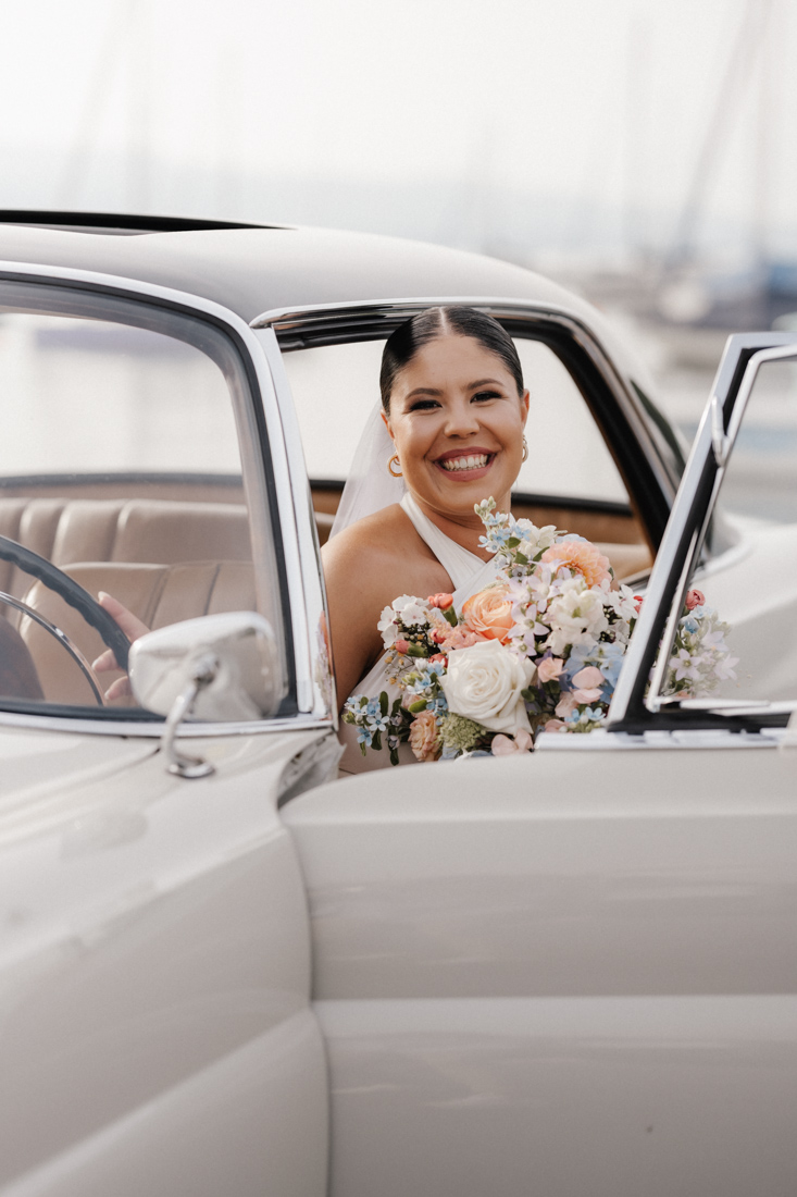 Frau im Auto mit Blumenstrauss lächelt und schaut in die Kamera