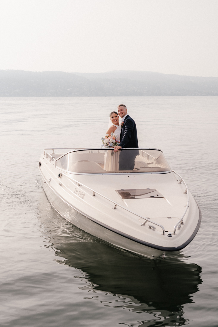 Paar auf weissem Motorboot mit Blumenstrauss und Wasser im Hintergrund