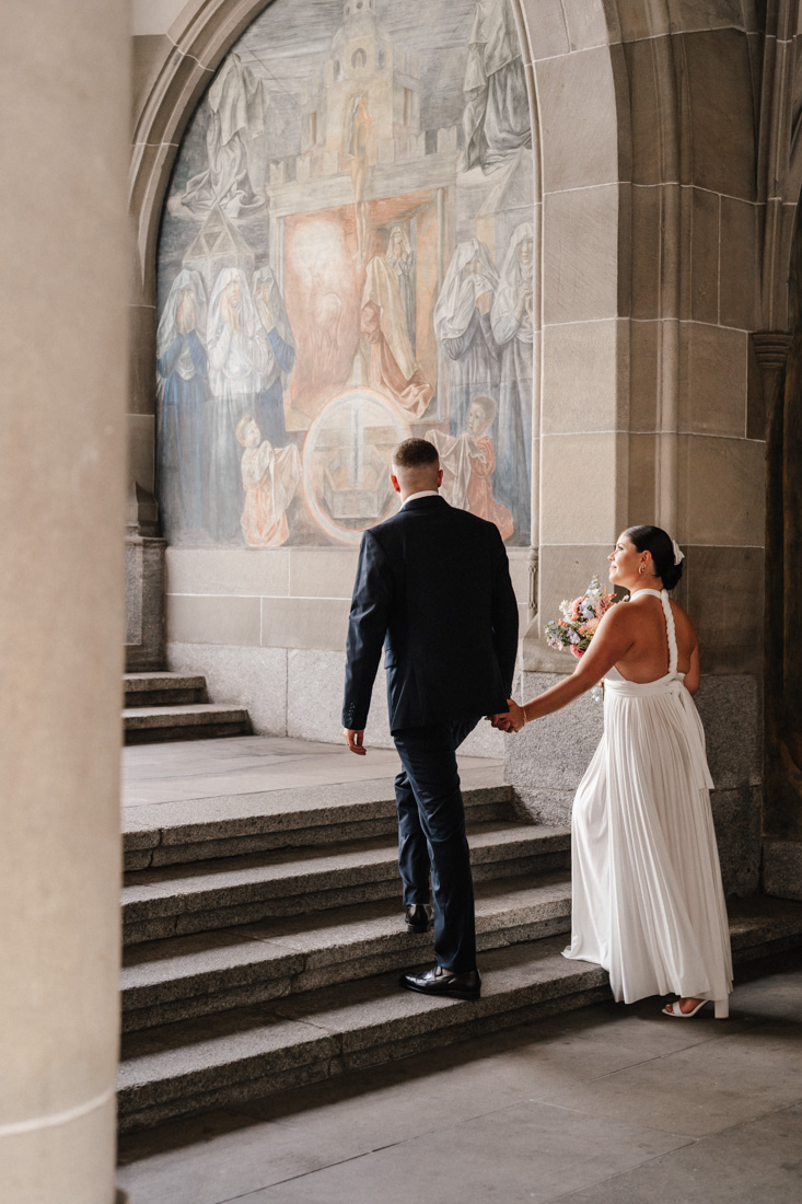 Paar geht Hand in Hand Treppe hoch Wandmalerei im Hintergrund