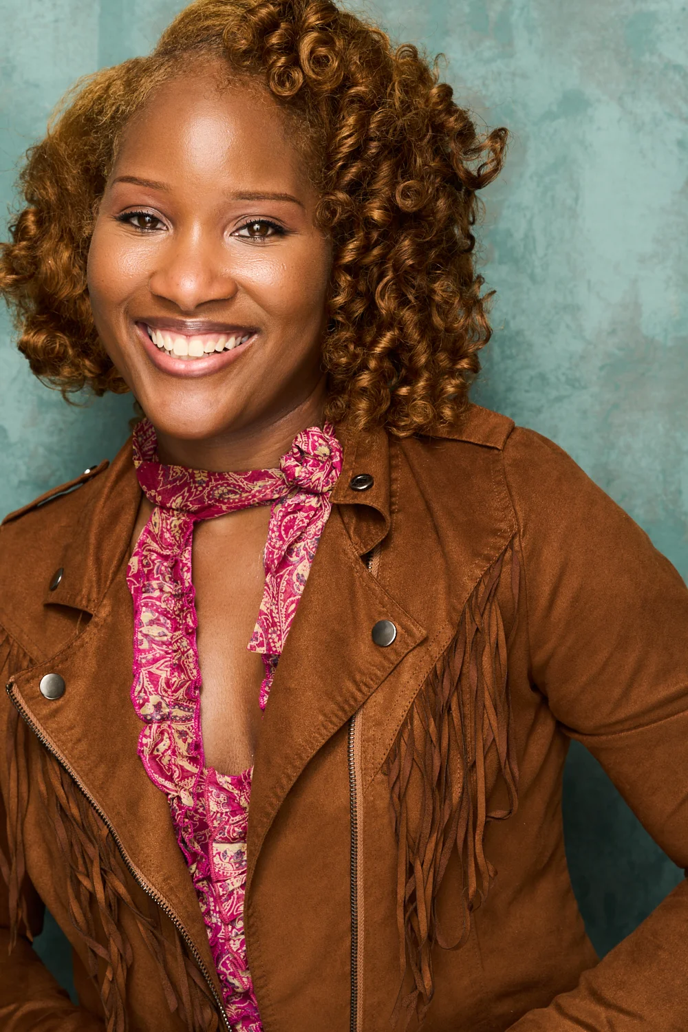 Marie Wilde smiling warmly with straight hair, wearing a light blue polo-style shirt against a soft blue backdrop