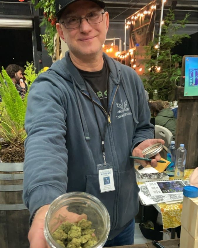 A person holding a glass jar of cannabis flower