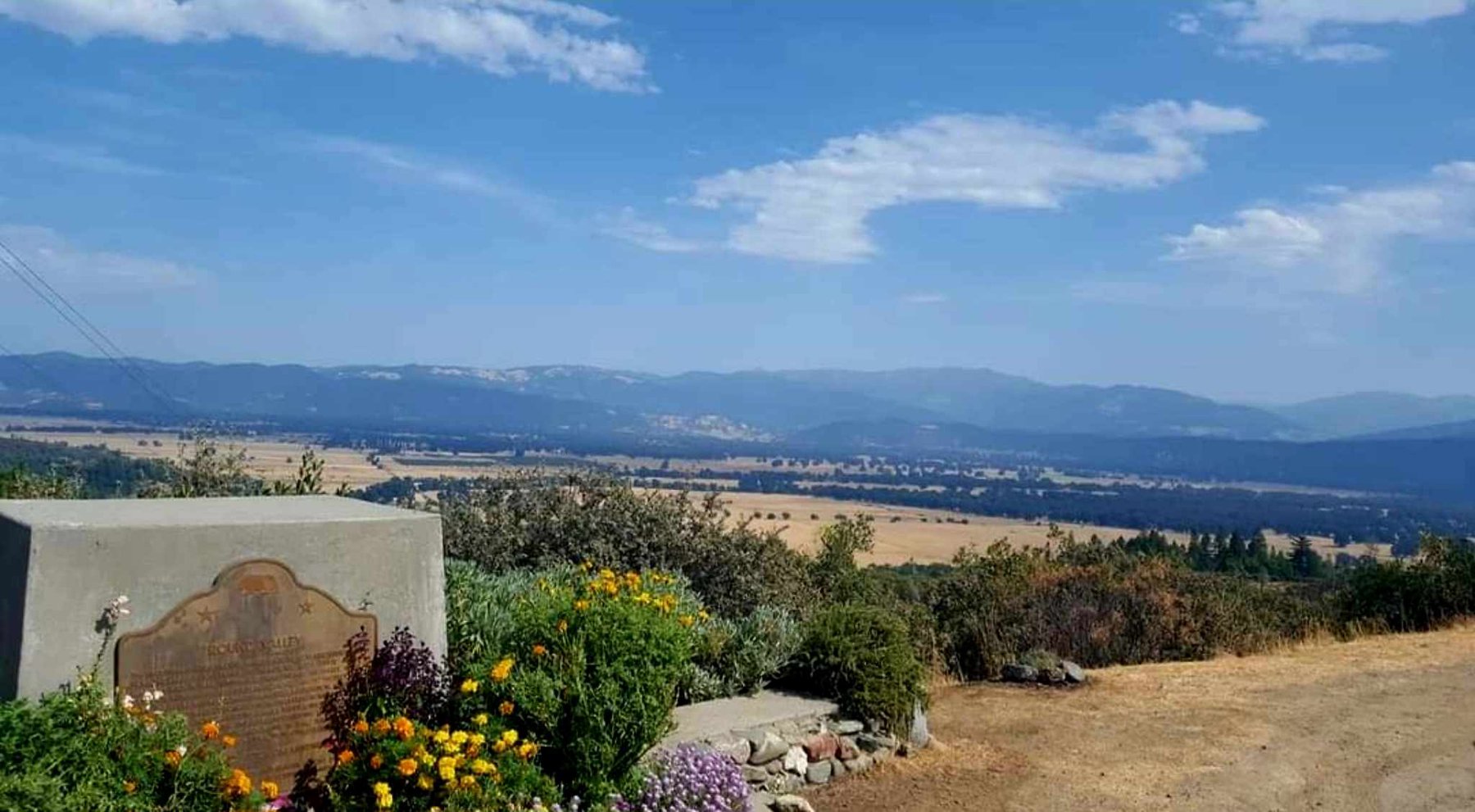 A view over the farm and valley in Covelo beneath a blue sky