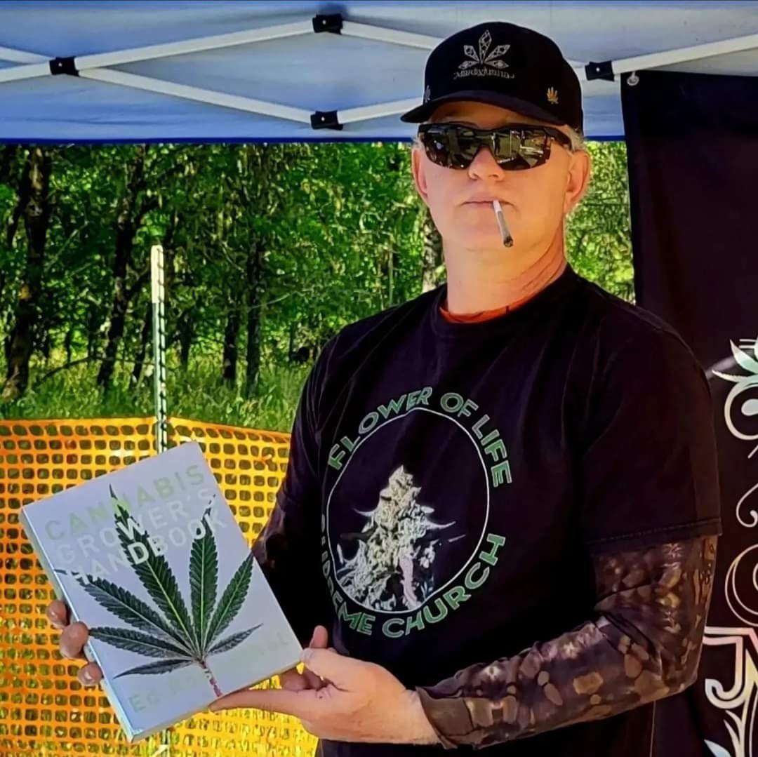 Marty holding Ed Rosenthal’s Cannabis Growers Handbook at an outdoor booth
