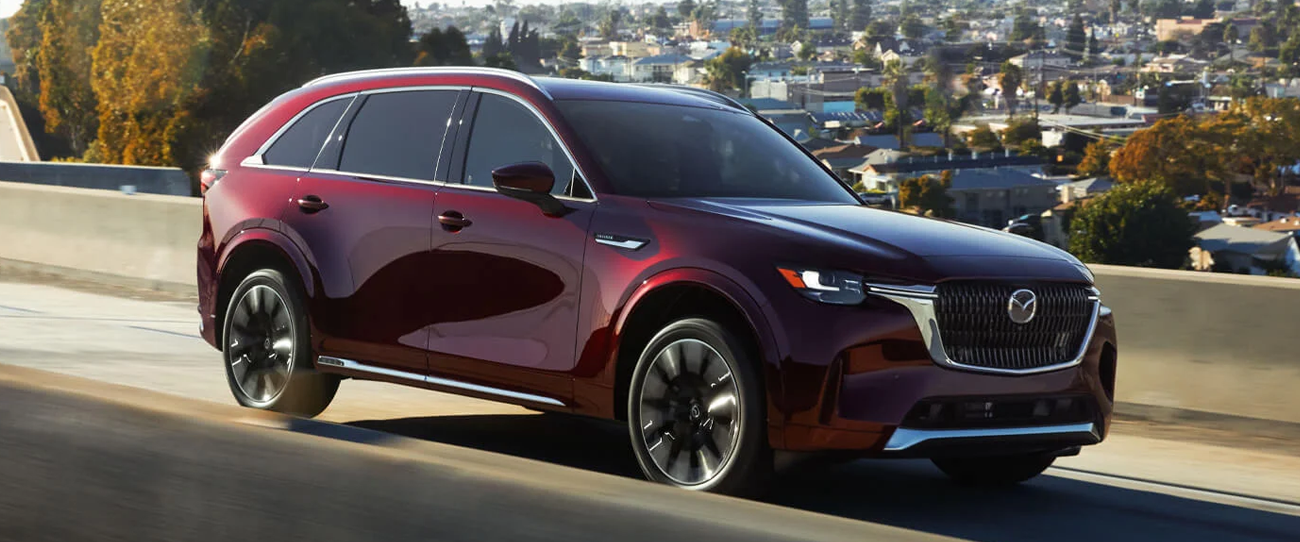 Vue 3/4 avant et latérale du Mazda CX-90 sur route en pleine puissance