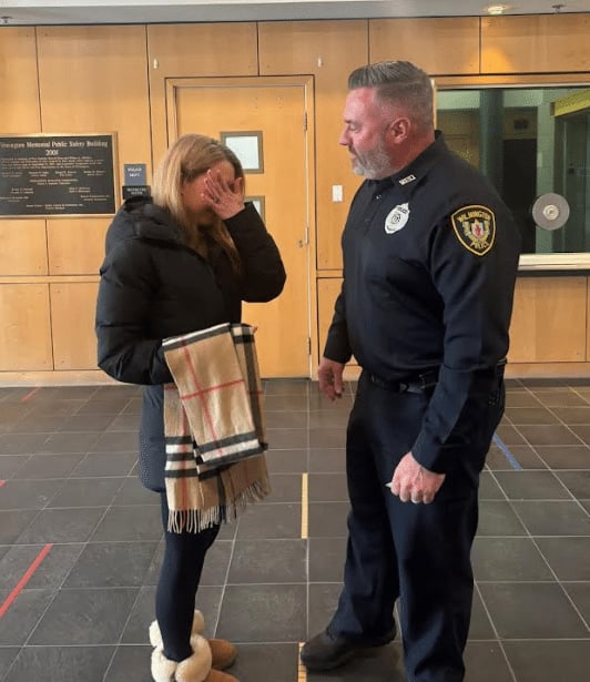 A woman wipes tears from her eyes as a Wilmington police detective returns her scarf