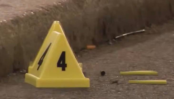 Close-up of evidence marker 4 next to a spent shell casing on pavement.