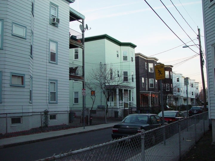 Triple-decker apartment buildings on a residential Cambridge, Massachusetts street.