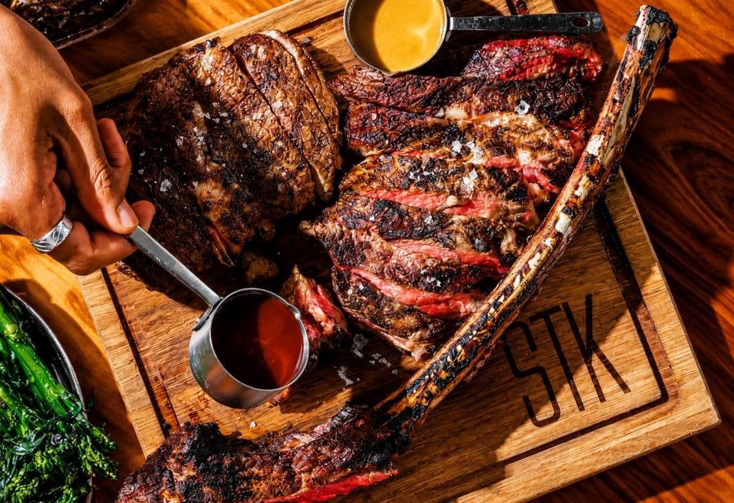 STK Steakhouse Wagyu tomahawk on a branded cutting board.