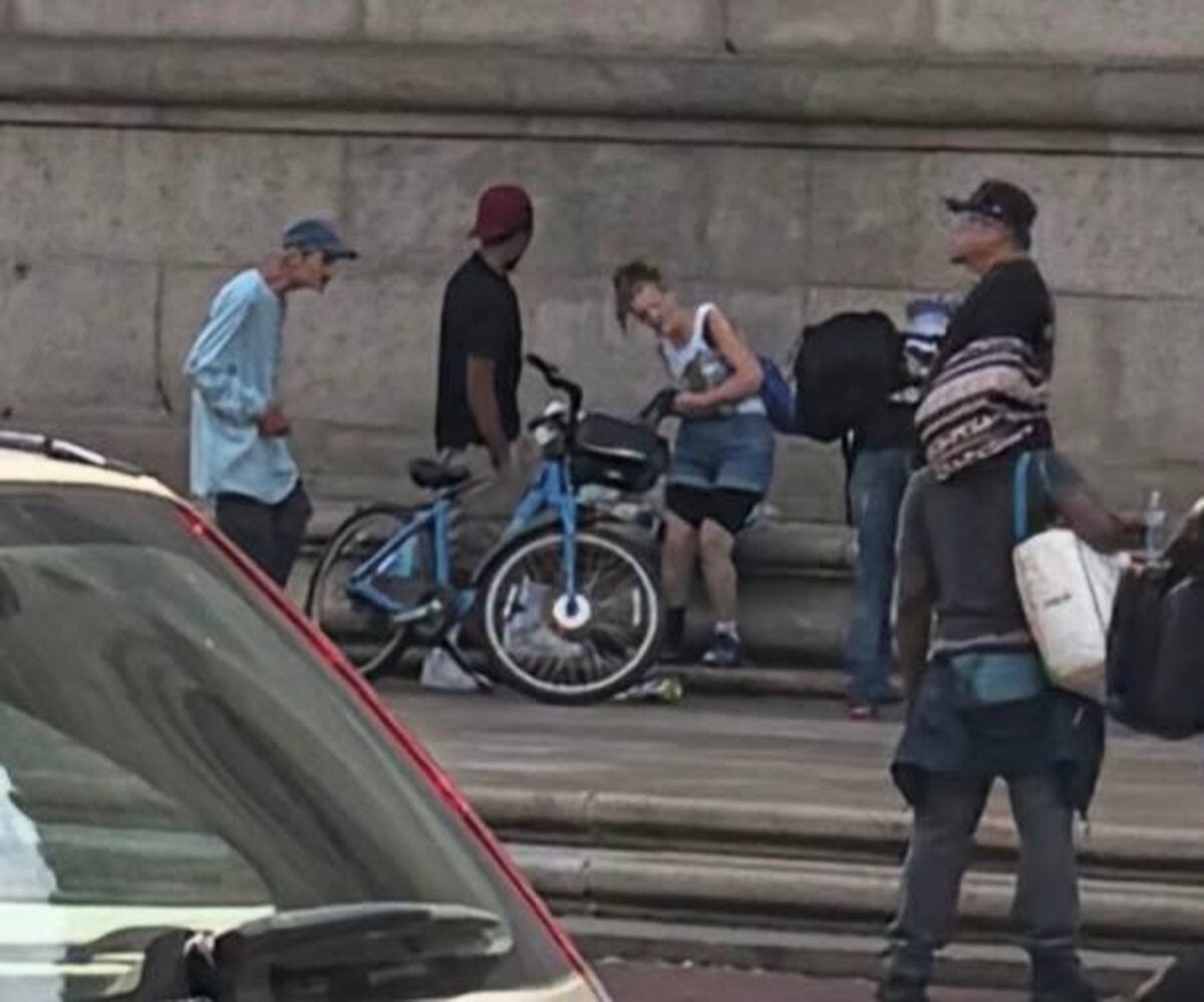 A group gathered on the stone steps of the Boston Public Library's Central Library in Copley Square, one shirtless and others visibly strung out.