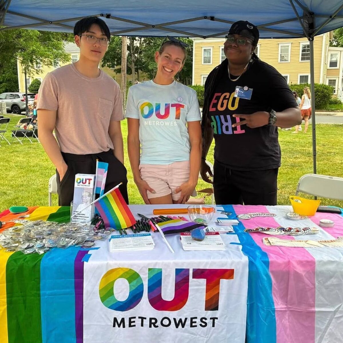 OUT MetroWest staff at a public tabling event with pride and trans flags on the tablecloth.