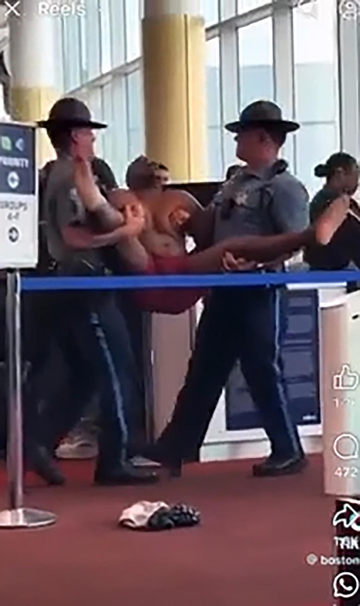 Boston meltdown at the gate: State troopers drag away the half-naked man as his underwear-clad stunt leaves Logan in shock.