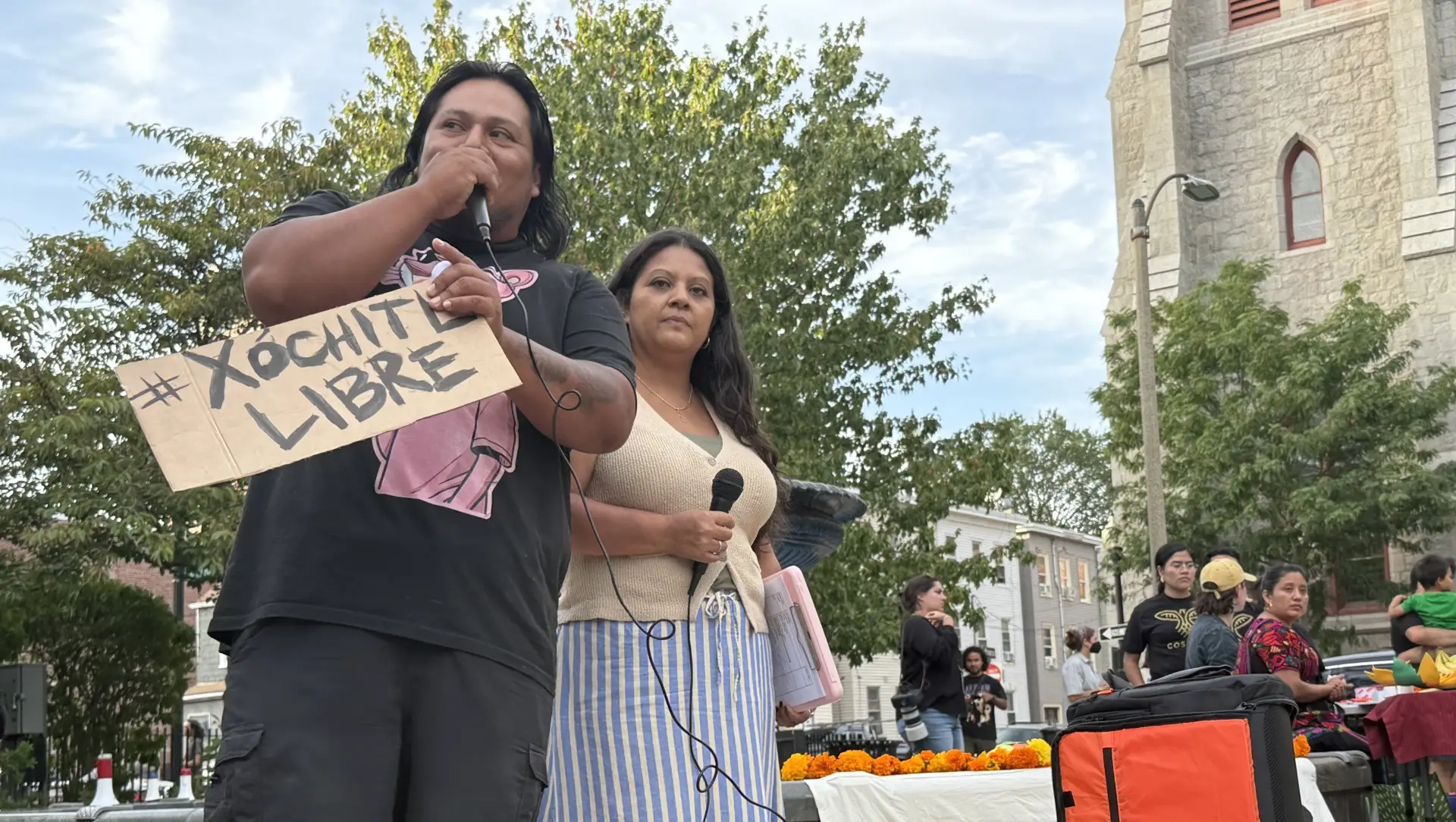 Josias Orozco holds a “#XochitlLibre” sign while speaking at a vigil in East Boston on Aug. 24, 2025, demanding ICE release his cousin Carlos Chang Barrios and fellow activist Catalina “Xochitl” Santiago. (Sarah Betancourt/GBH News)