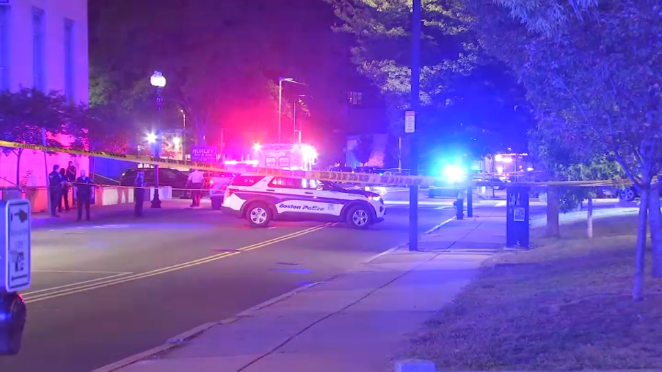 Police lights and yellow tape flood Roxbury’s Kenilworth Street after a midnight gun battle left a Boston officer shot and a suspect riddled with bullets. (Credit: NBC Boston)