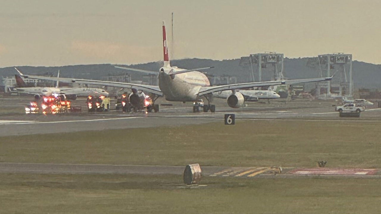 Fire trucks swarm the halted Swiss Air jet on Logan’s runway after its engine spat flames like a blowtorch — a terrifying sight for passengers moments away from liftoff. (Credit: Marc Richards)