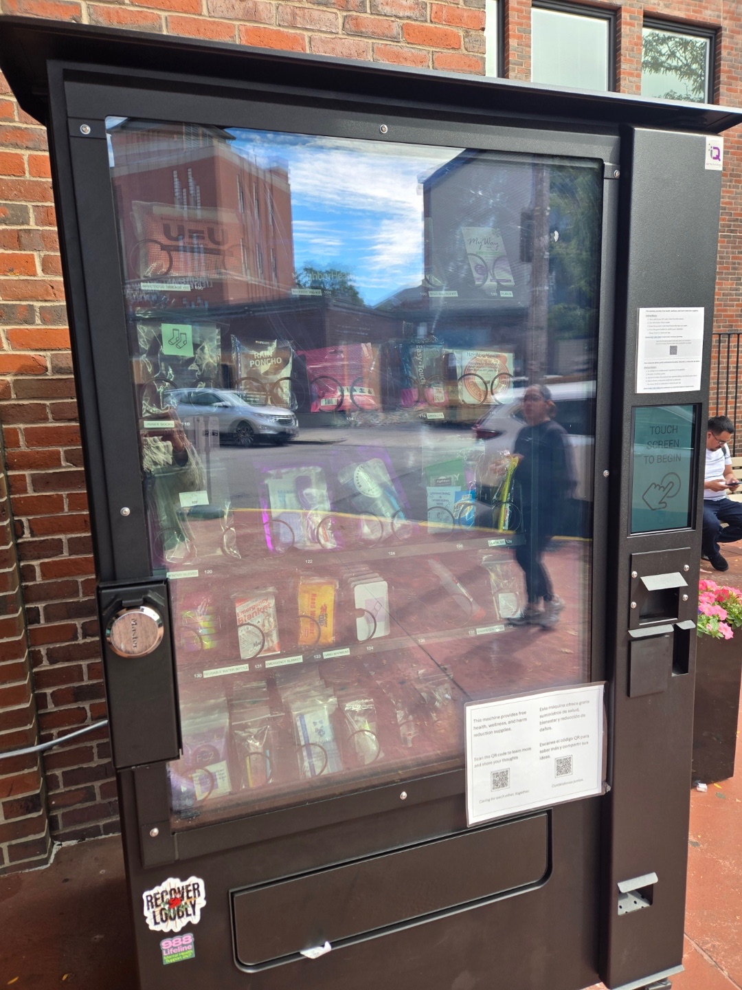 The taxpayer-funded “drug machine” bolted outside an East Boston health center glows with bright buttons and shelves lined with Narcan, needles, and overdose kits — a sight critics say turns the sidewalk into a supply hub for addicts.
