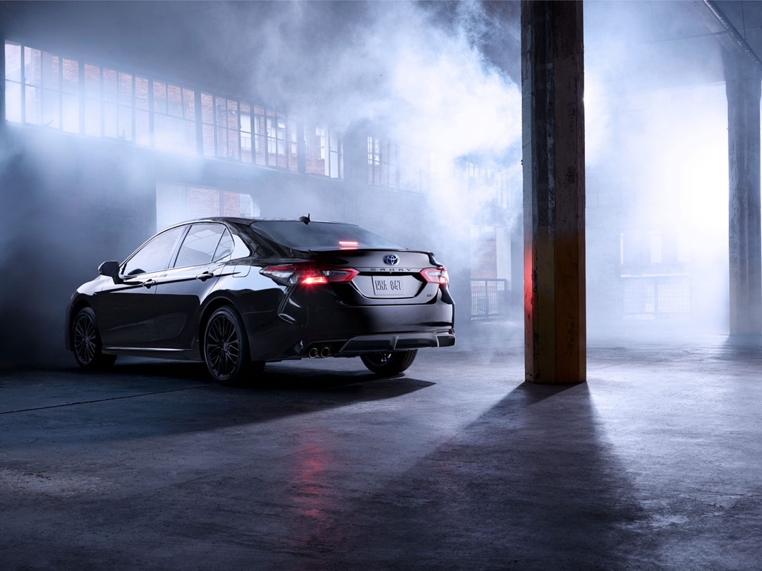 Toyota Camry hybride usagée dans un bâtiment pour représenter une berline hybride plus puissante et confortable.