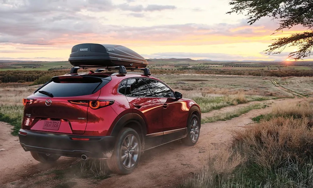 Mazda CX-30 rouge sur un chemin de campagne pour représenter un VUS compact sportif et économique.