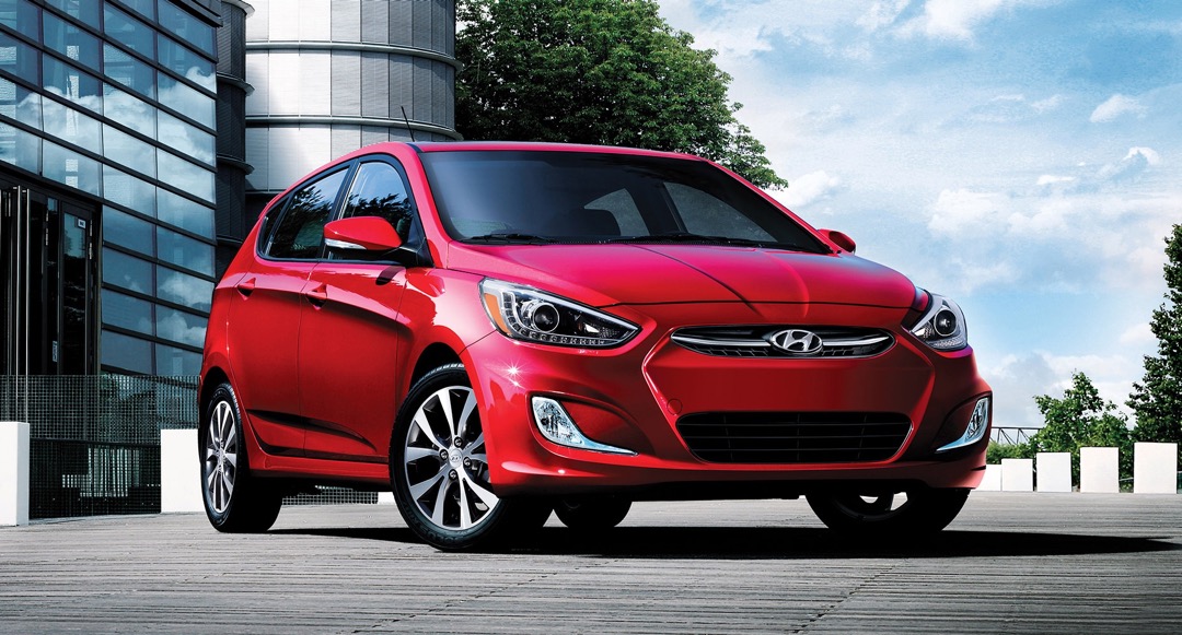 Hyundai Accent 2017 rouge vue de trois quarts avant en environnement urbain, berline usagée économique parmi les voitures les moins chères au Québec.