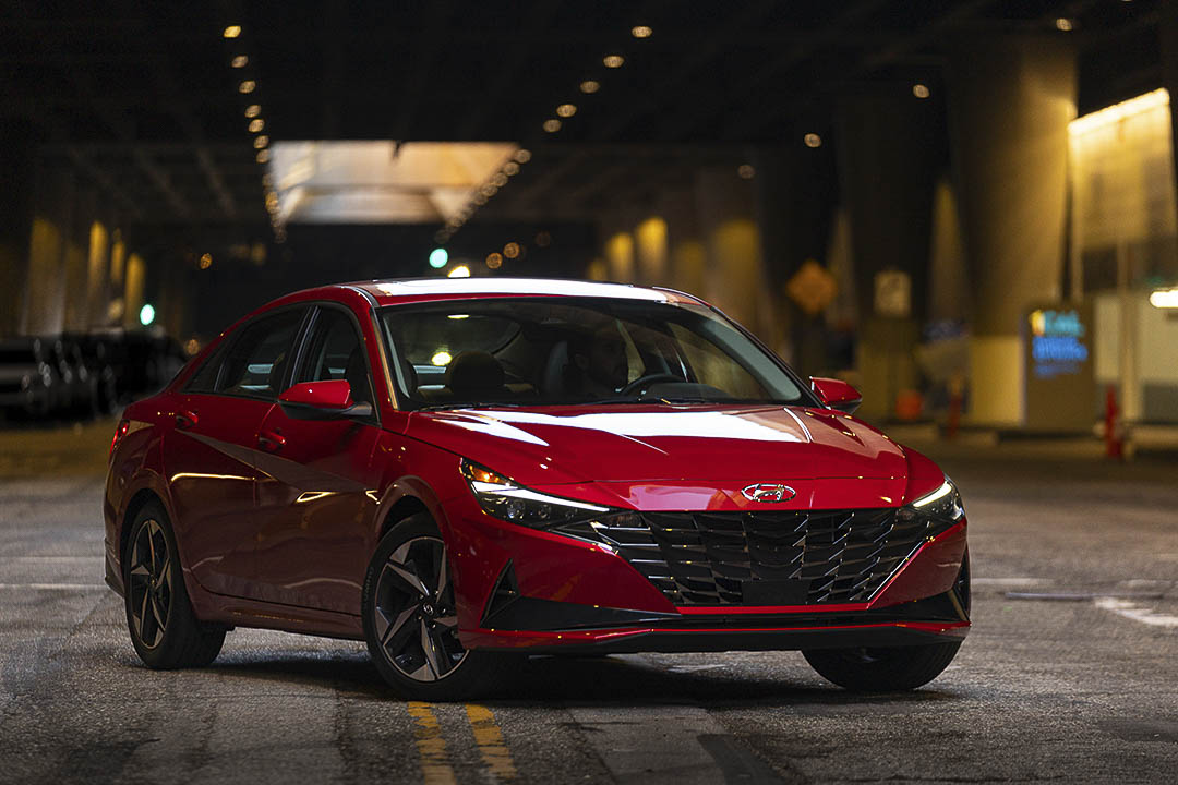 Hyundai Elantra 2021 rouge vue de trois quarts avant dans un tunnel urbain, berline compacte au design sportif offrant un excellent rapport qualité-prix au Québec.