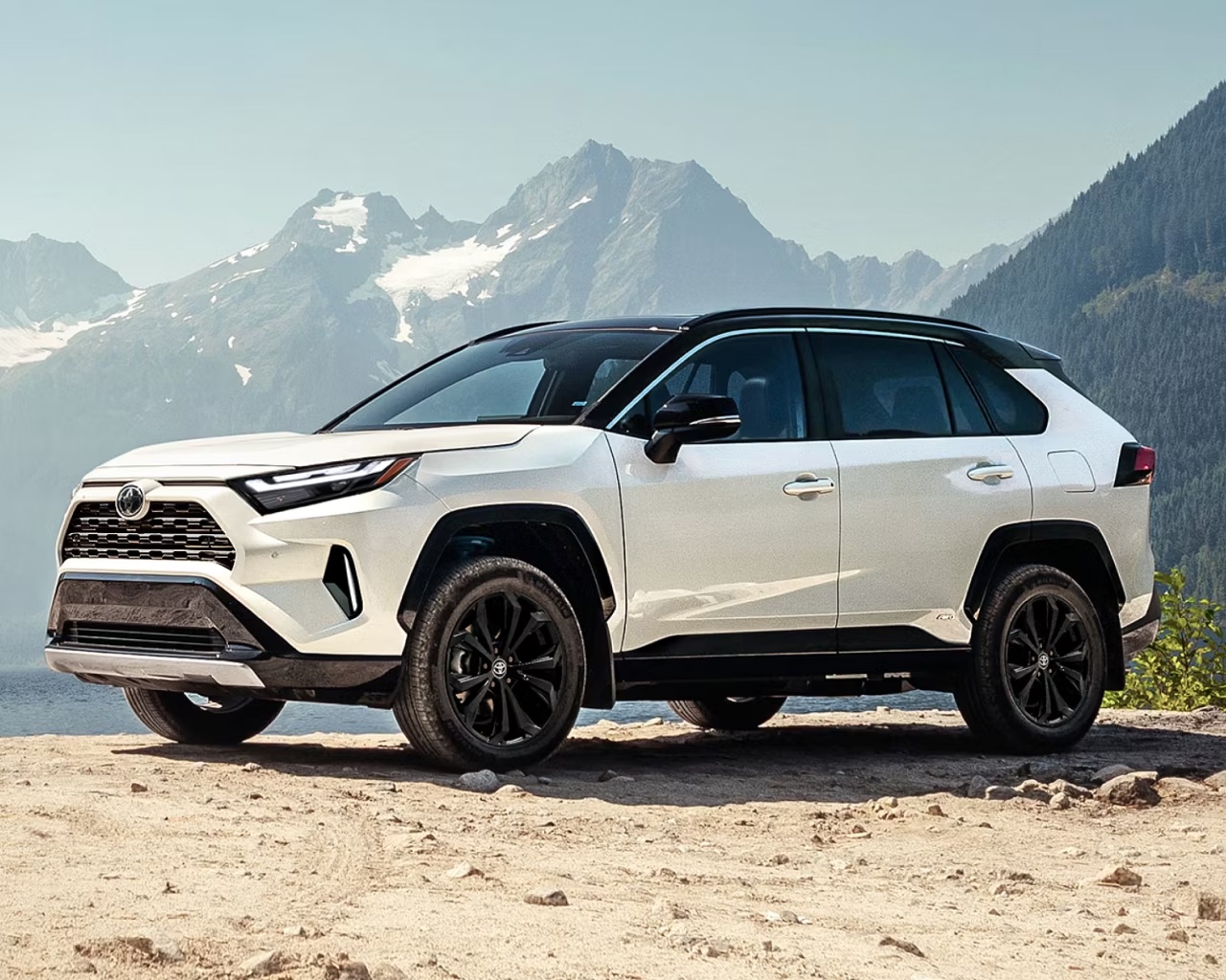 Toyota RAV4 AWD blanc vu de trois quarts avant en environnement montagneux, VUS compact à traction intégrale réputé pour sa fiabilité et sa conduite sécuritaire toute l’année.