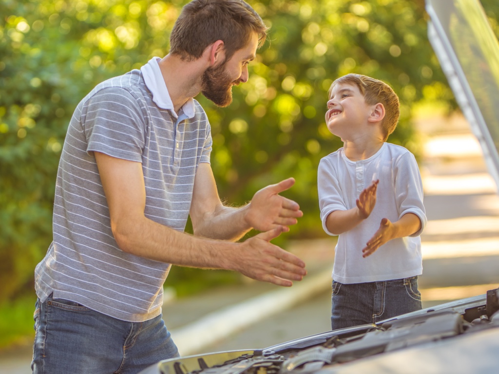 Père et enfant devant une voiture ouverte lors d’un entretien de voiture au printemps pour prévenir l’usure et la corrosion.