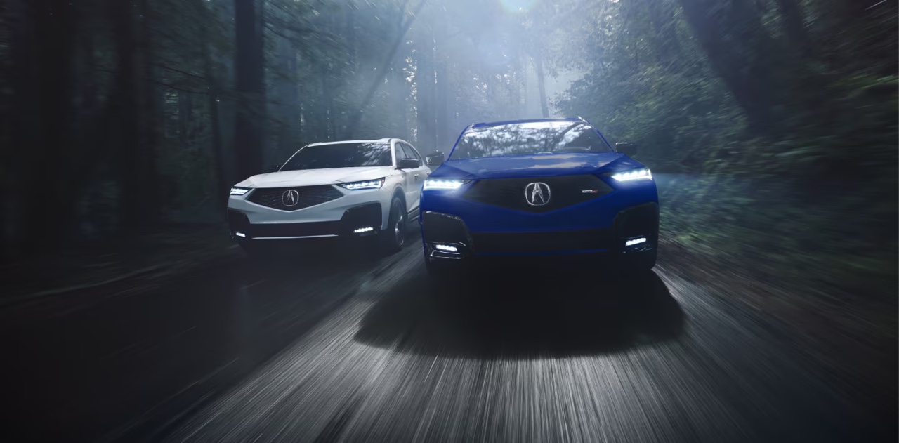 Acura MDX vu de face en conduite nocturne sur route forestière, VUS de luxe alliant performance, fiabilité et technologies avancées.