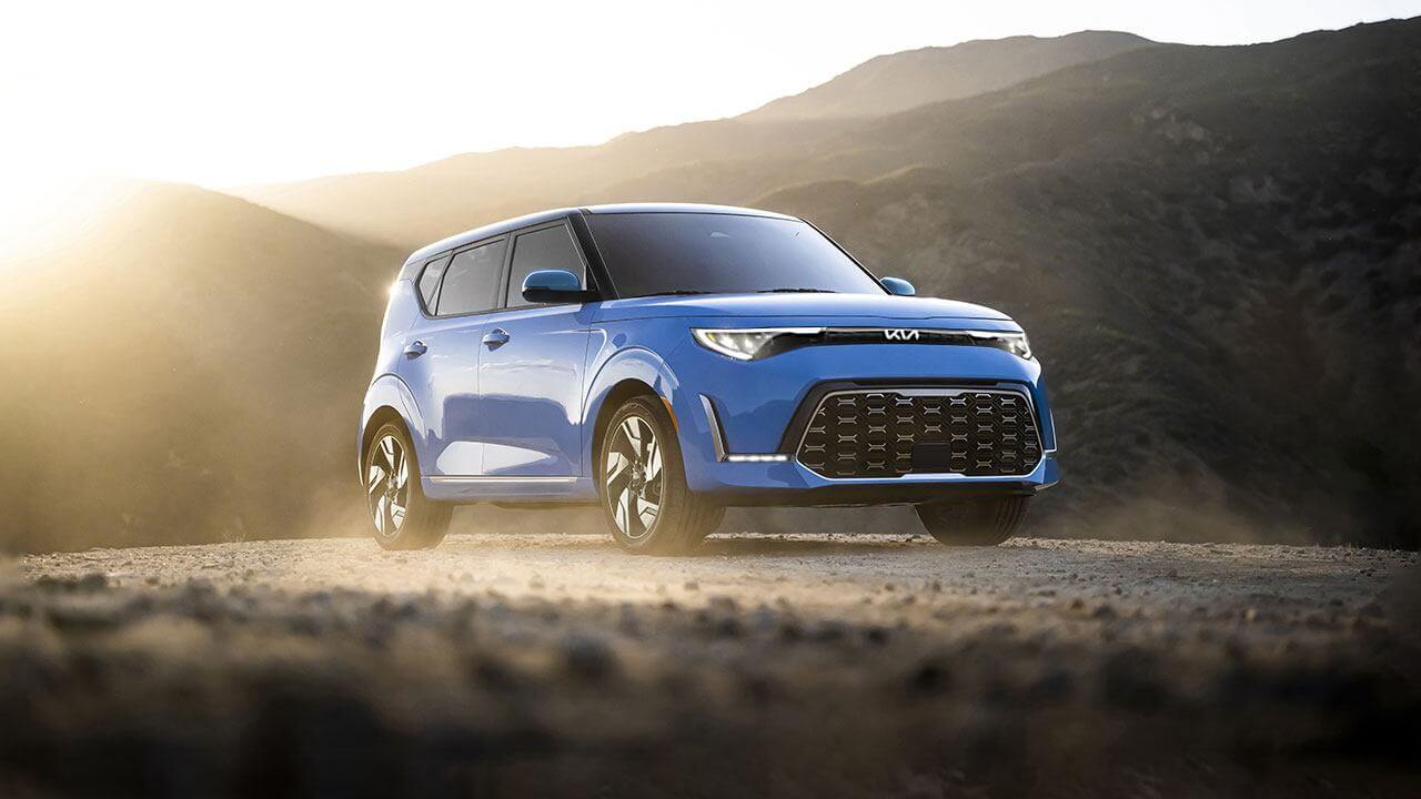 Kia Soul EV bleu sur une route de montagne pour représenter un VUS électrique abordable d’occasion.