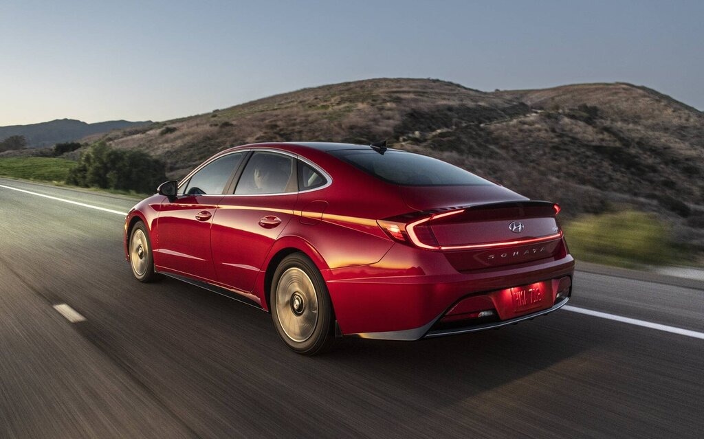 Hyundai Sonata hybride usagée rouge sur la route pour représenter une berline hybride confortable et bien équipée.
