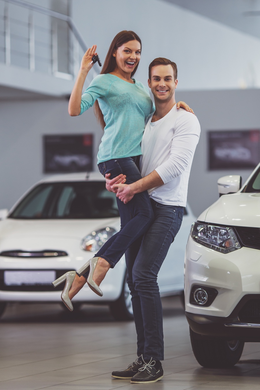 Couple heureux recevant les clés d’un véhicule usagé en concession, représentant une transaction automobile et le paiement des taxes applicables au Québec.