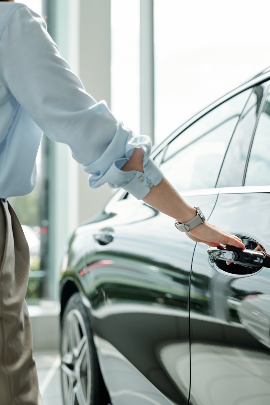 Client ouvrant la portière d’un véhicule usagé en salle d’exposition, illustrant l’achat d’une voiture et les obligations fiscales à prévoir au Québec.