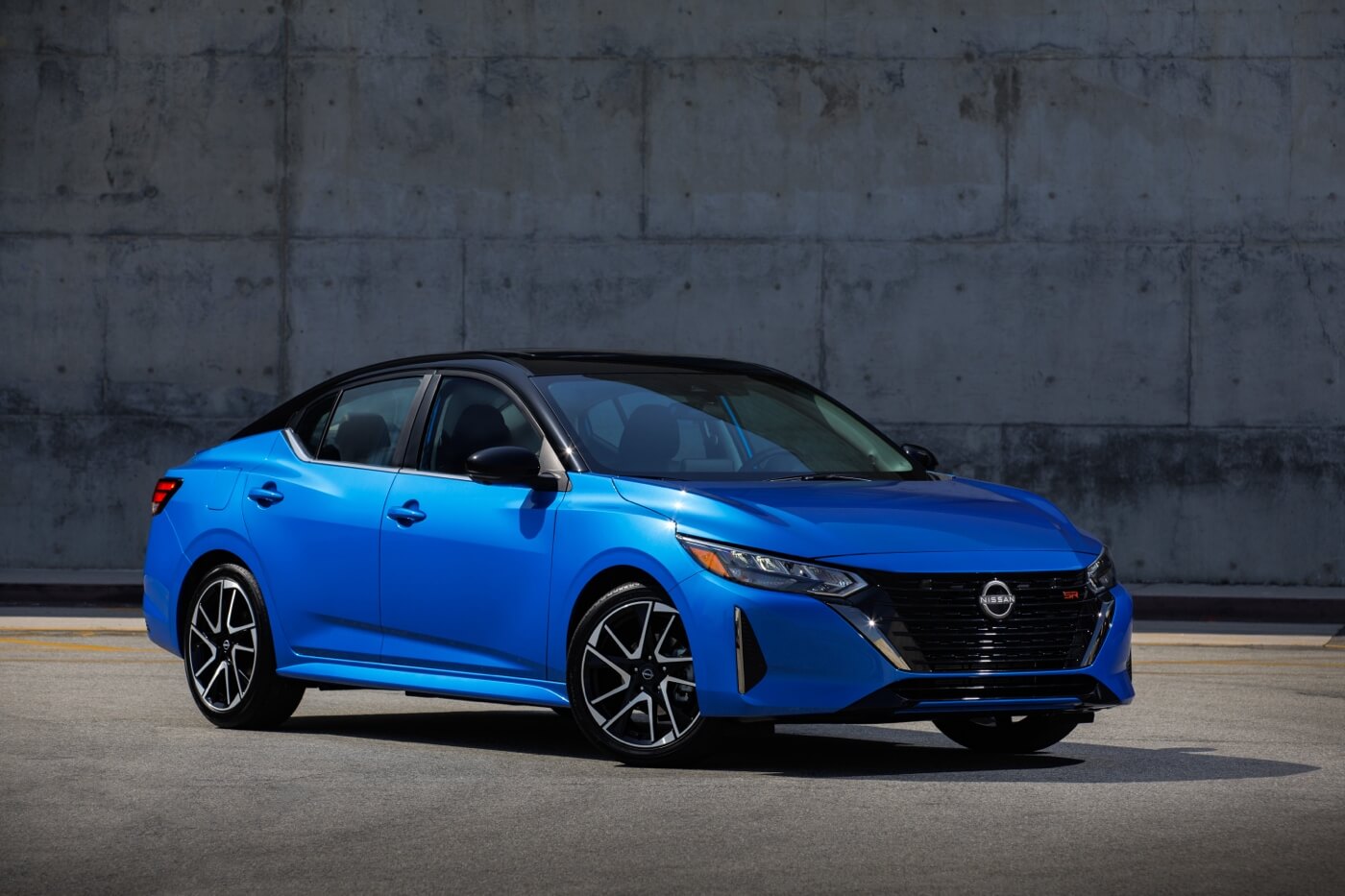Nissan Sentra 2024 bleue vue de trois quarts avant stationnée en milieu urbain, berline abordable offrant de bonnes performances et une faible consommation d’essence.