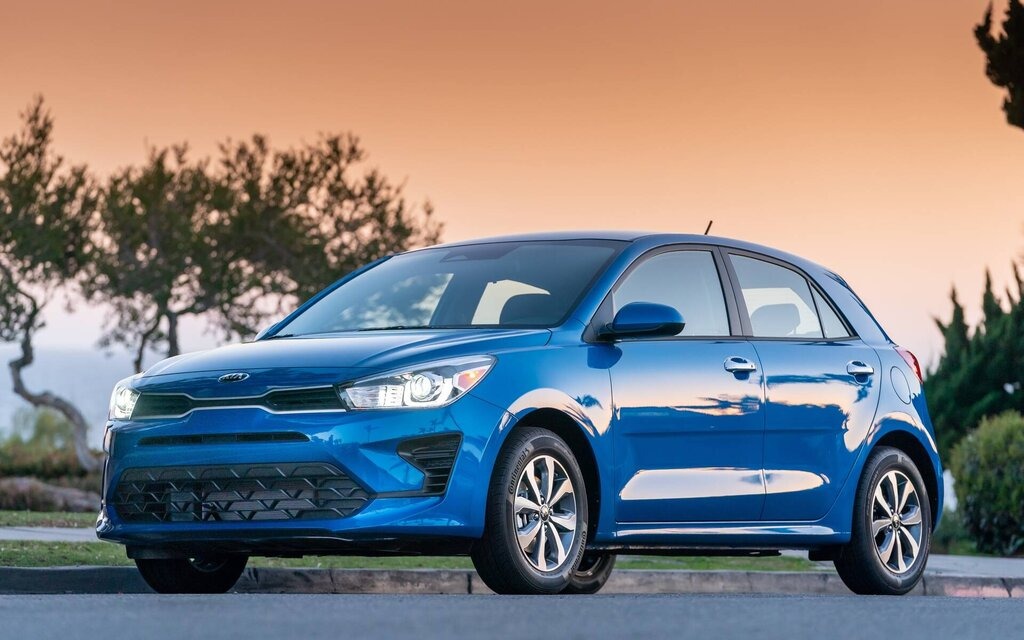 Kia Rio bleue stationnée au coucher du soleil pour représenter une sous-compacte usagée économique en essence.