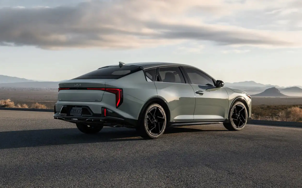 Kia K4 2025 grise vue de trois quarts arrière sur route dégagée, berline neuve moderne offrant un excellent rapport qualité-prix au Québec.