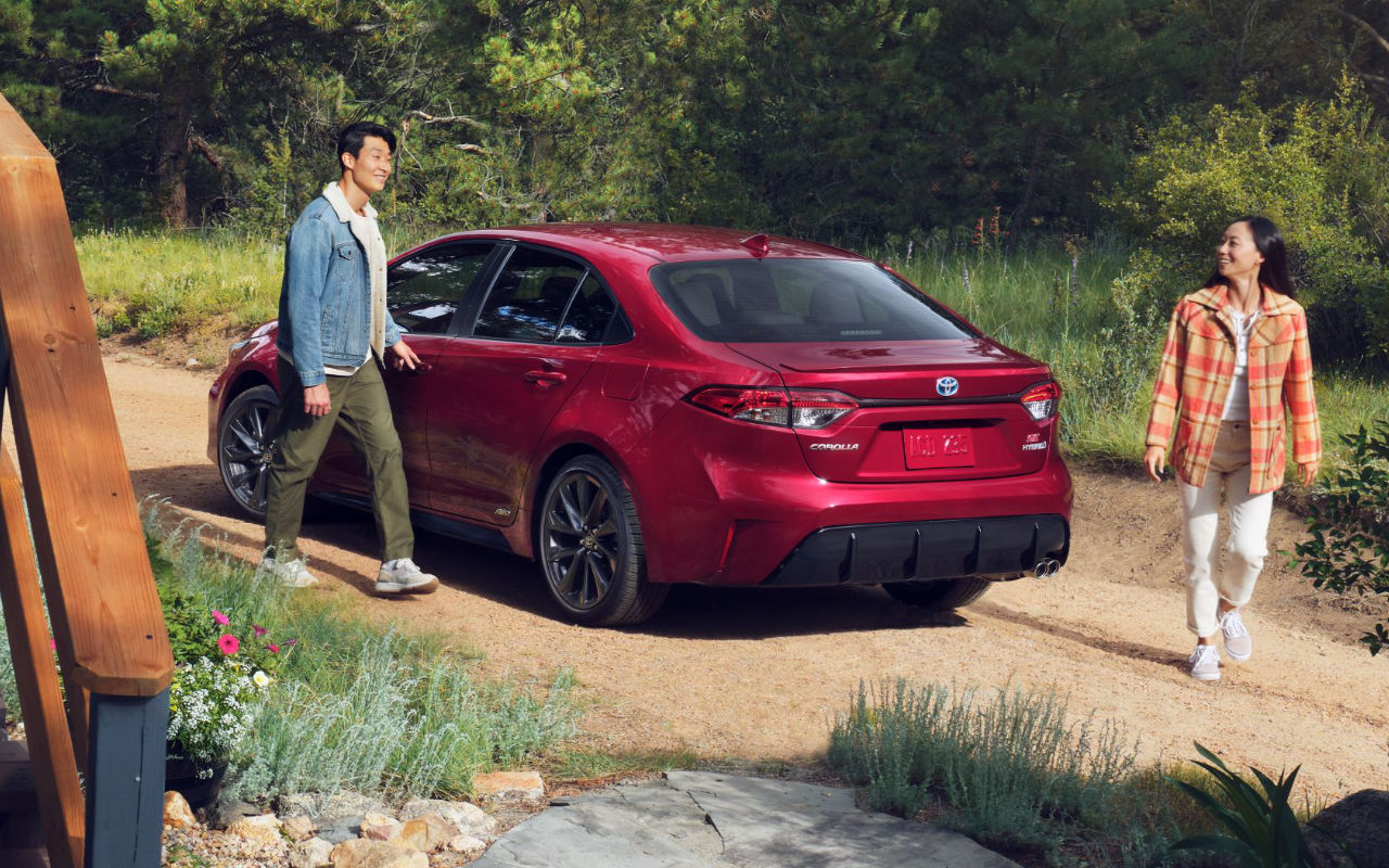 Toyota Corolla hybride usagée rouge sur un chemin pour illustrer une berline hybride économique et fiable.