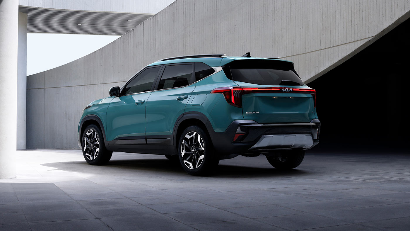 Kia Seltos turquoise dans une architecture moderne pour illustrer un VUS compact à faible consommation.