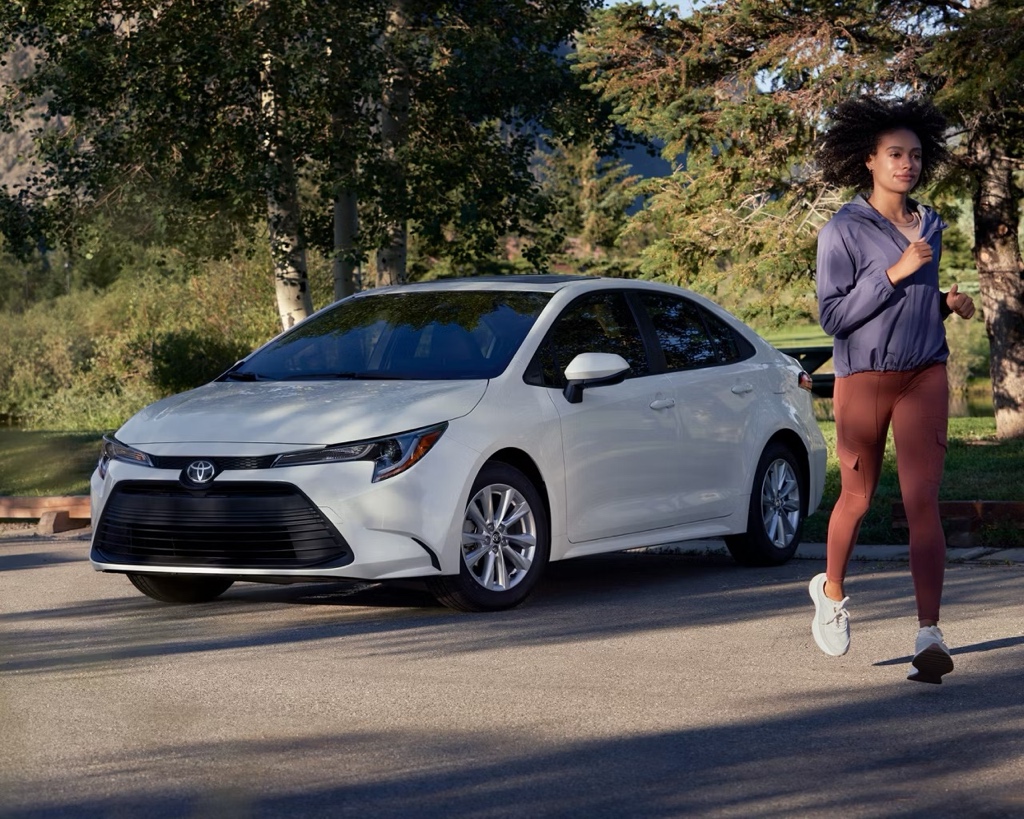 Toyota Corolla blanche stationnée en nature pour illustrer une citadine usagée fiable et économique en essence.
